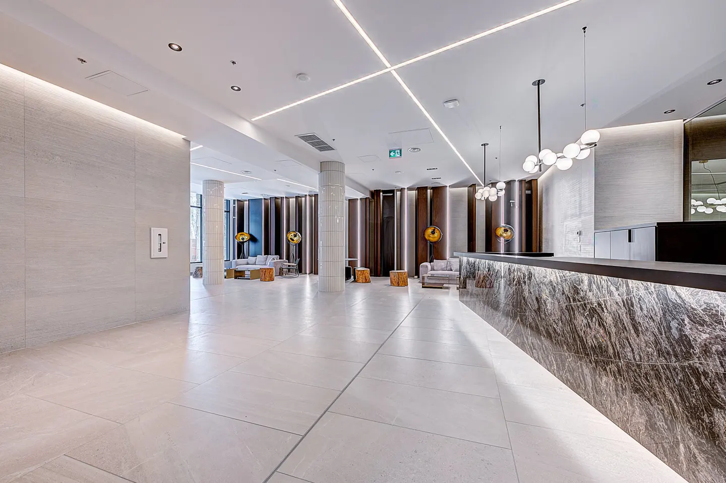 Modern lobby with marble reception desk, white tile floors, and lounge area. Linear lighting accents the ceiling.