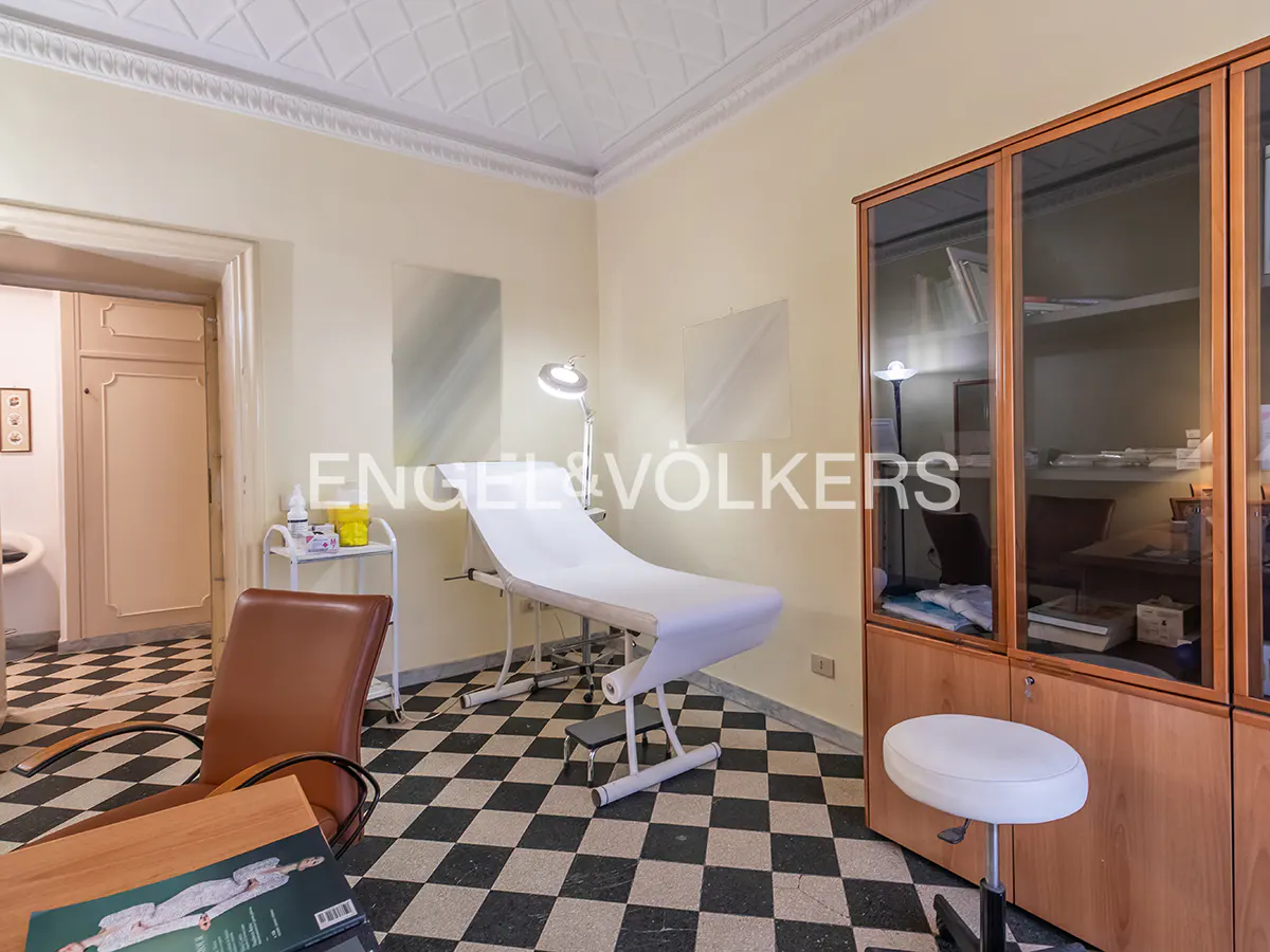 A room with a black and white checkered floor, a white examination table, and a wooden cabinet.