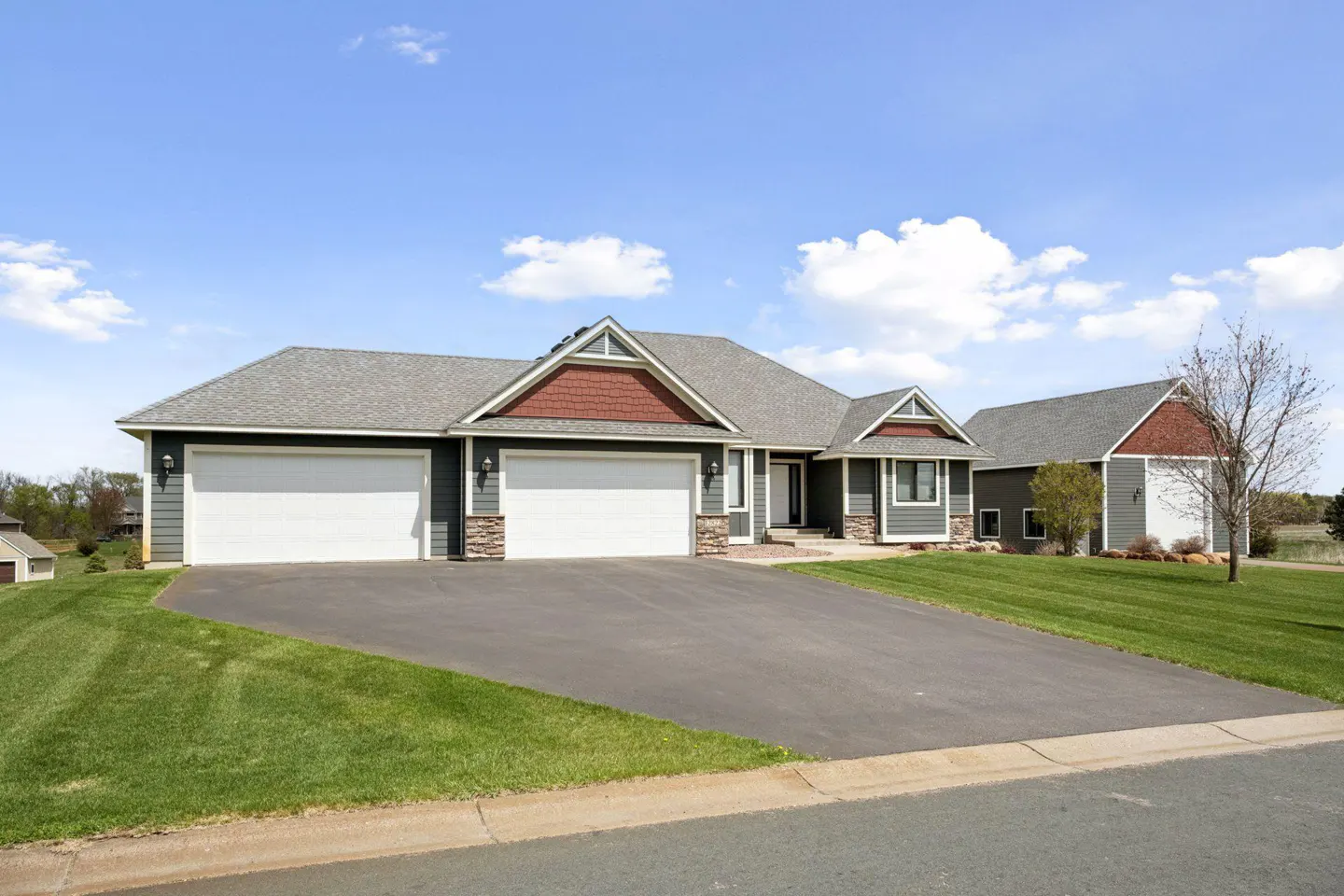 A single-family home with a three-car garage, gray siding, and a large driveway.