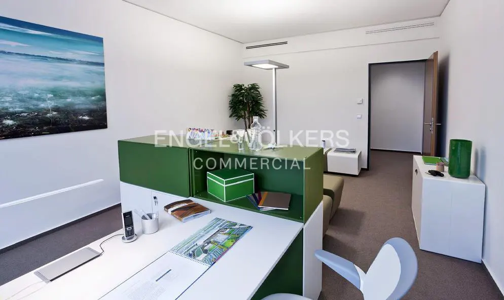 Office space with white walls, a green and white desk, and a landscape painting on the wall.