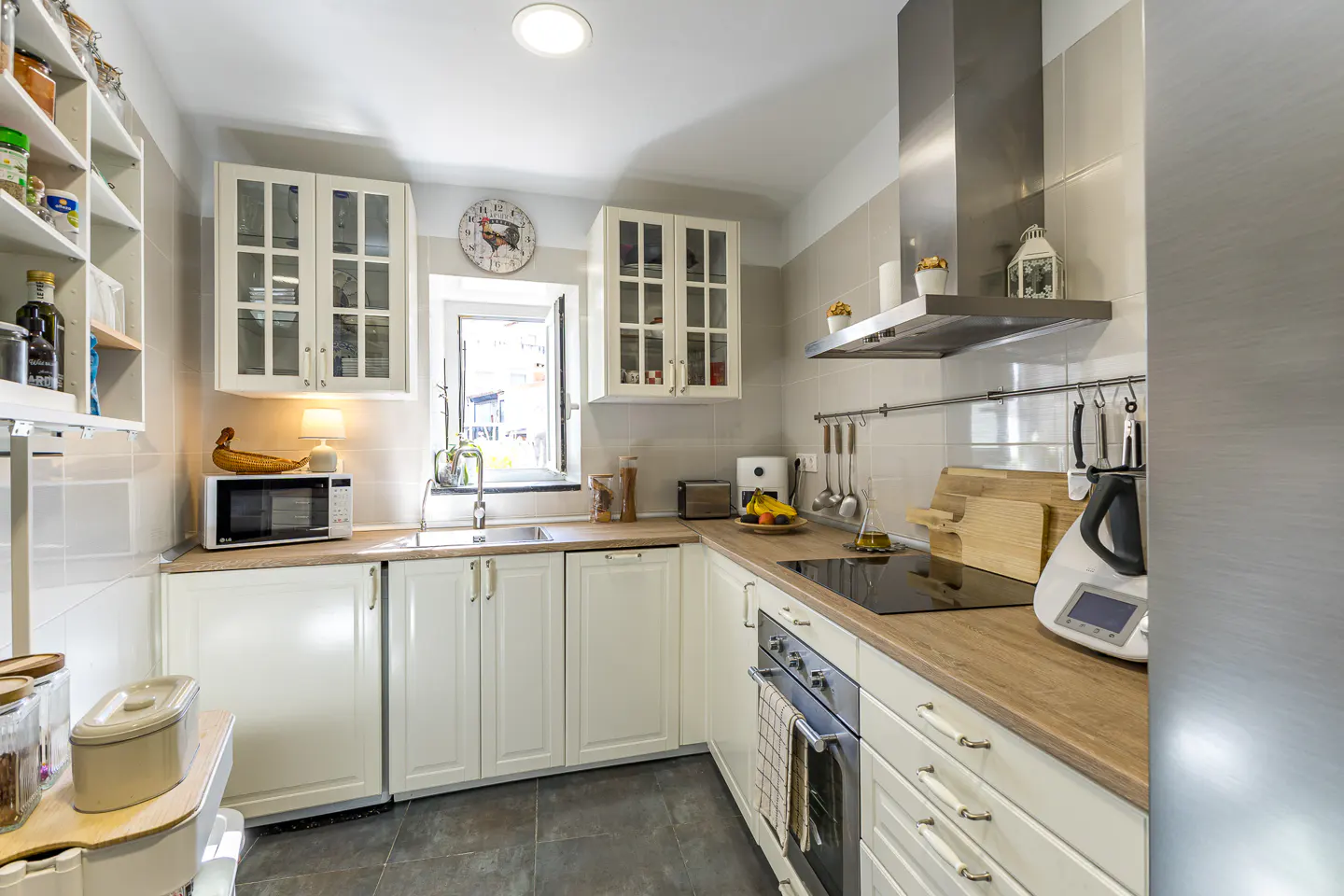 Bright kitchen with white cabinets, wood countertops, and stainless steel appliances. A window sits above the sink.