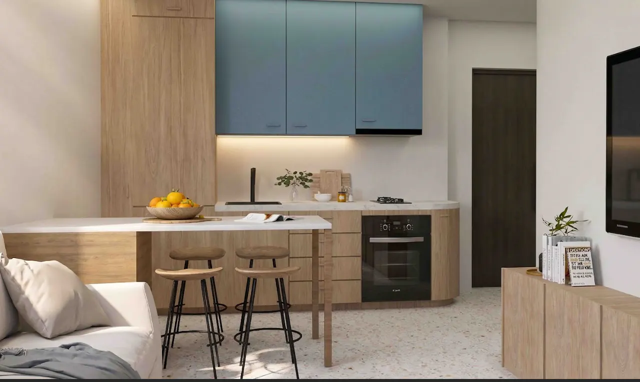 A modern kitchen with blue cabinets, wood accents, a white countertop, and three stools. A bowl of oranges sits on the counter.