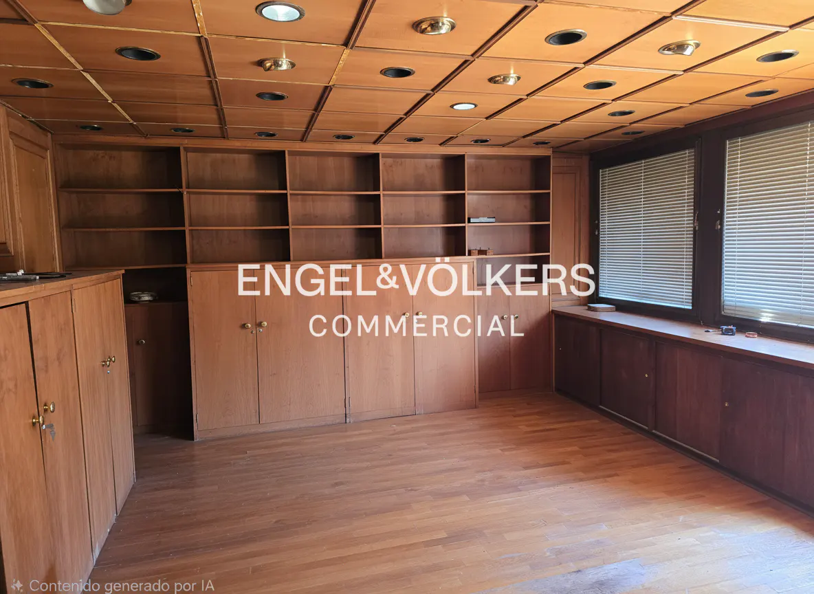 A wood-paneled office with built-in shelves and cabinets, and a wood floor. Two windows with blinds are on the right.