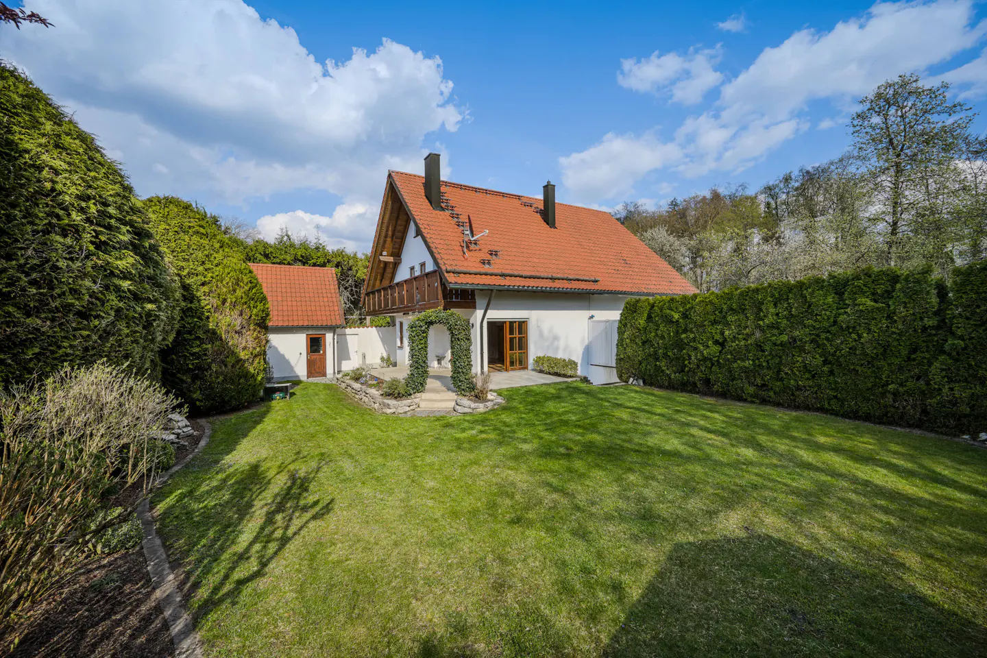 A white house with a red tile roof and green lawn on a sunny day.