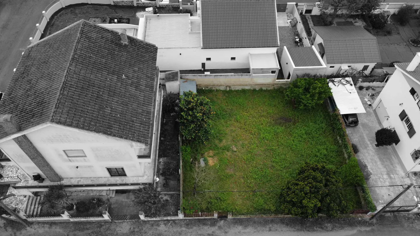 Aerial view of a green lawn surrounded by grayscale houses and streets.