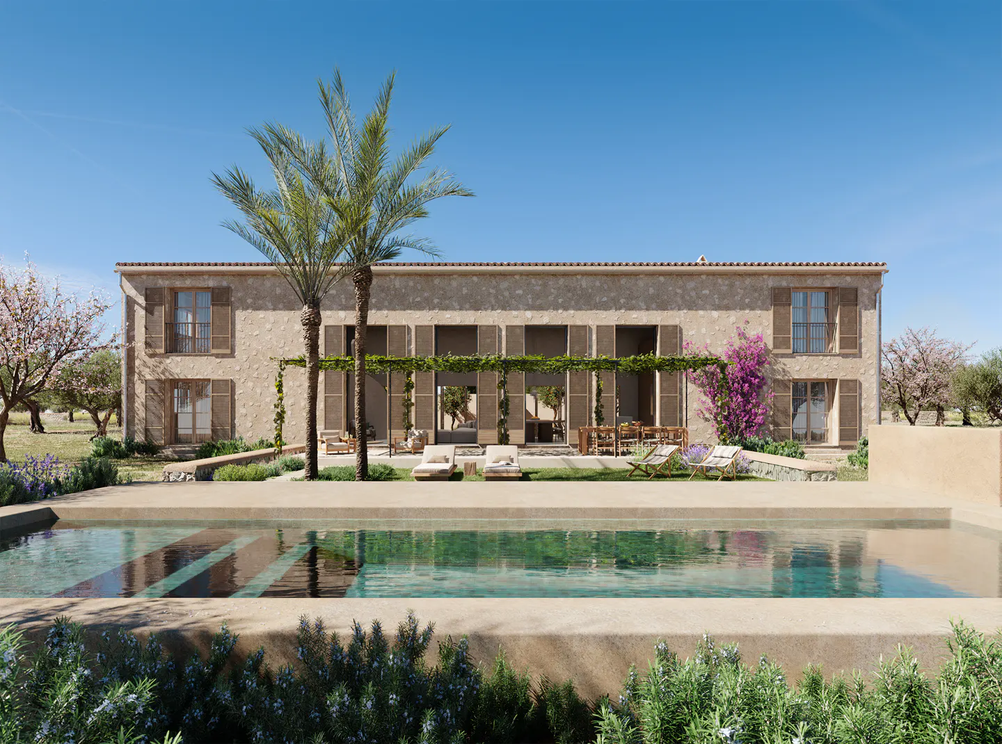 Exterior of a tan stone house with brown shutters, palm trees, and a pool in the foreground.