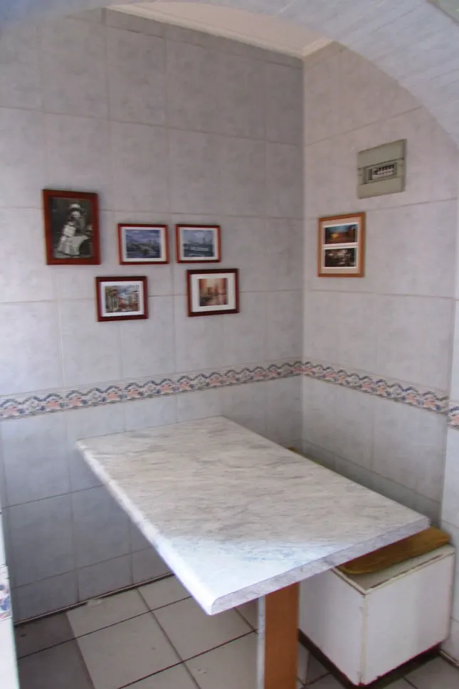 A tiled kitchen area with a marble table and framed pictures on the wall.