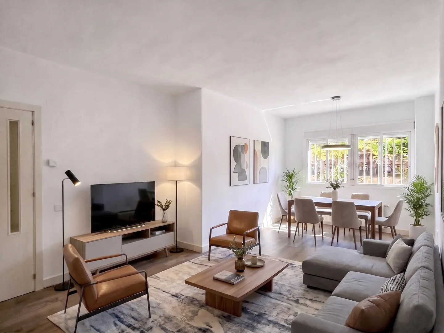 Bright, modern living room with a gray sectional sofa, brown leather chairs, and a dining table near a window.