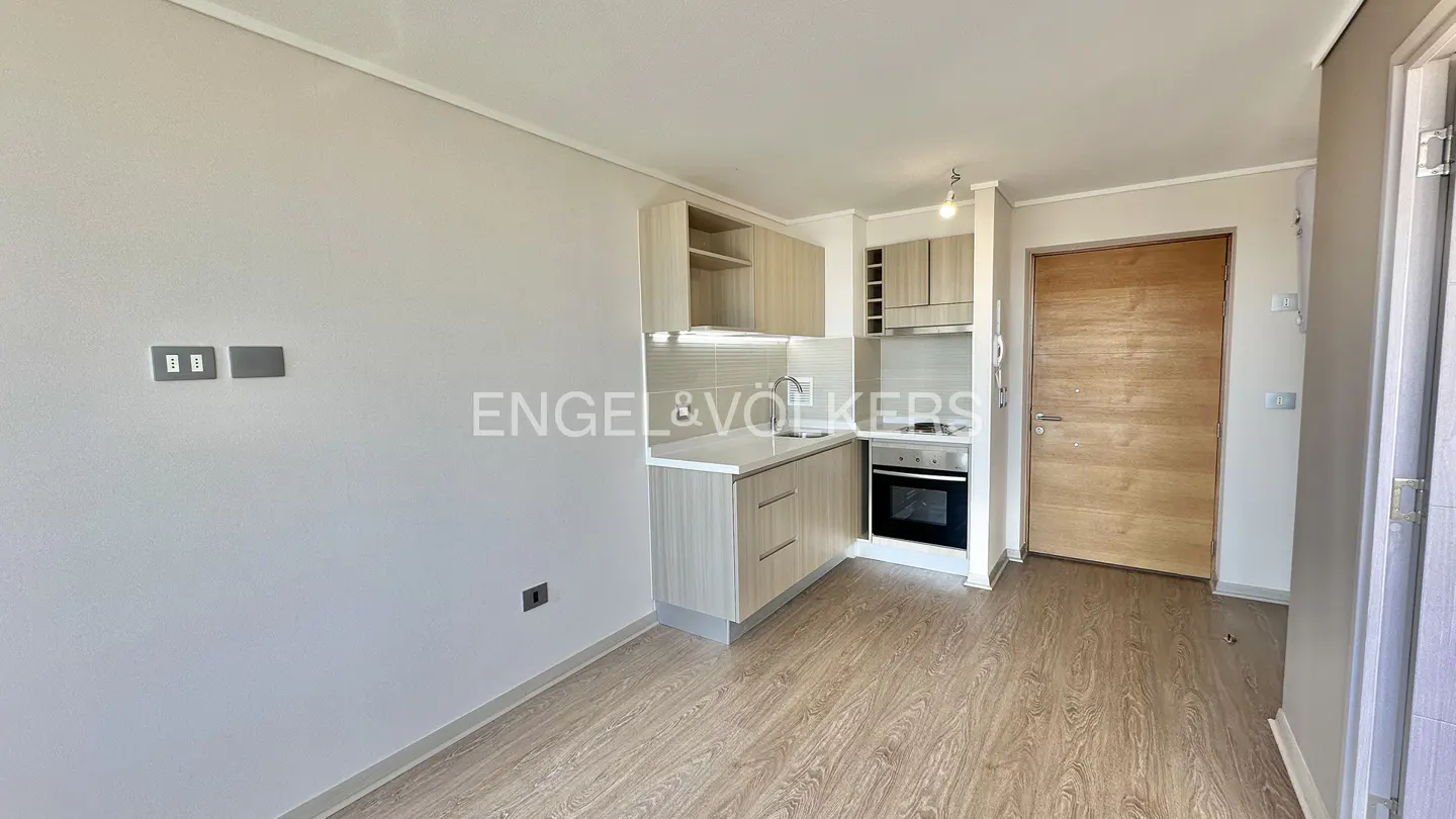 A bright, modern apartment interior with wood-look floors, light wood cabinets, and a stainless steel oven.