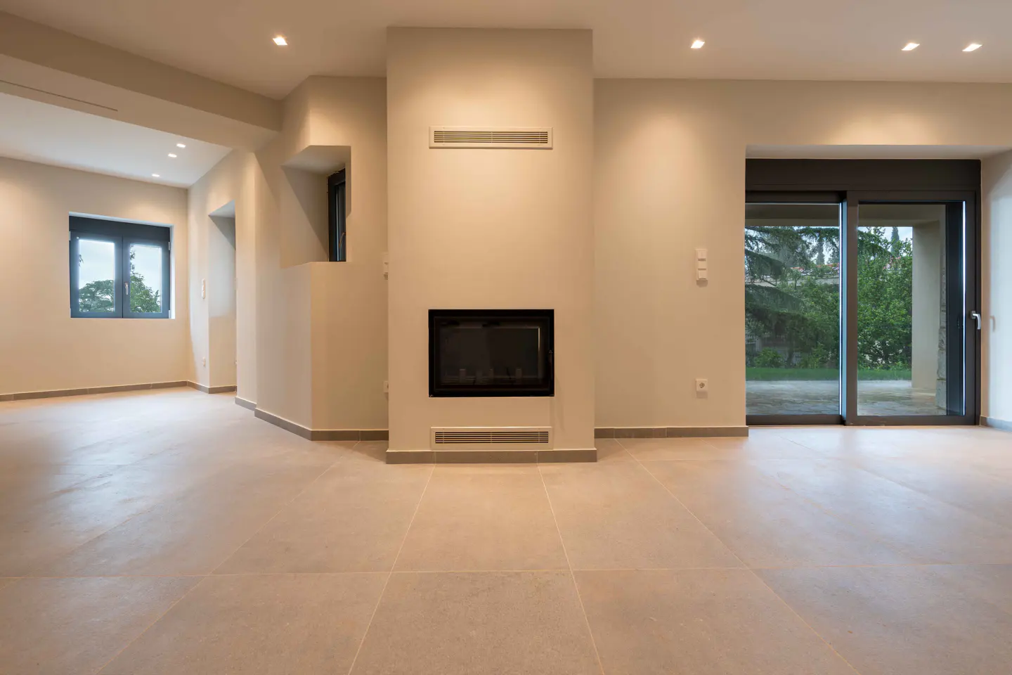 Beige living room with a black fireplace, a window, and sliding glass doors to the outside.
