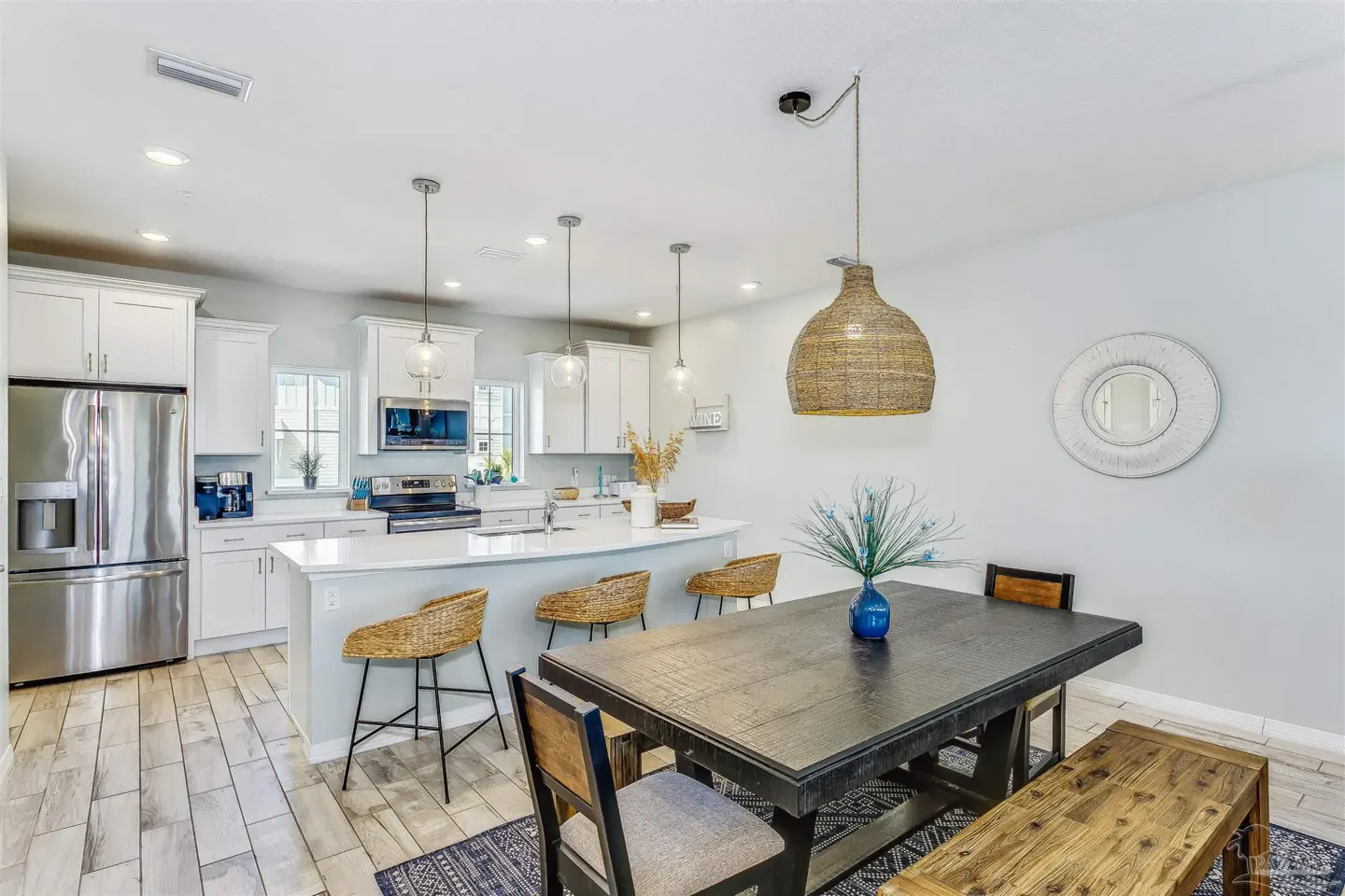 Open-concept kitchen and dining area with white cabinets, stainless steel appliances, and a dark wood dining table.