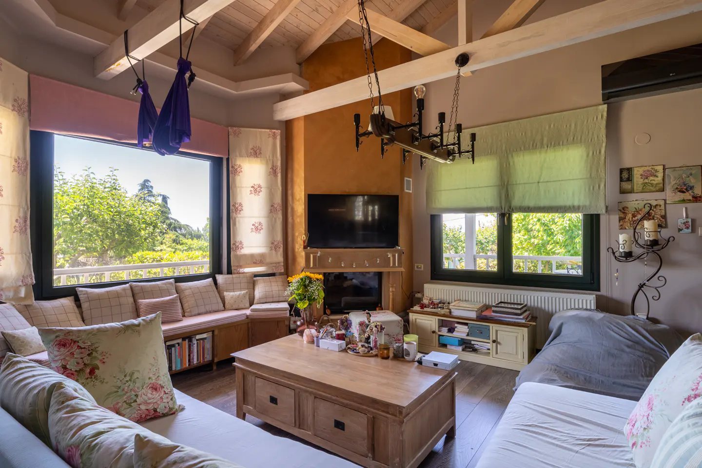 Bright living room with a wooden ceiling, large windows, and comfortable seating. A wooden coffee table sits in the center of the room.