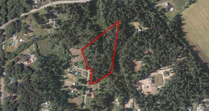 Aerial view of a wooded lot outlined in red, surrounded by rural residential properties and a nearby road.