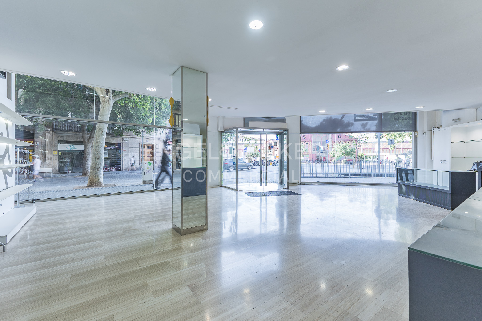 Bright, empty retail space with marble floors and large windows. Street view visible through the glass.