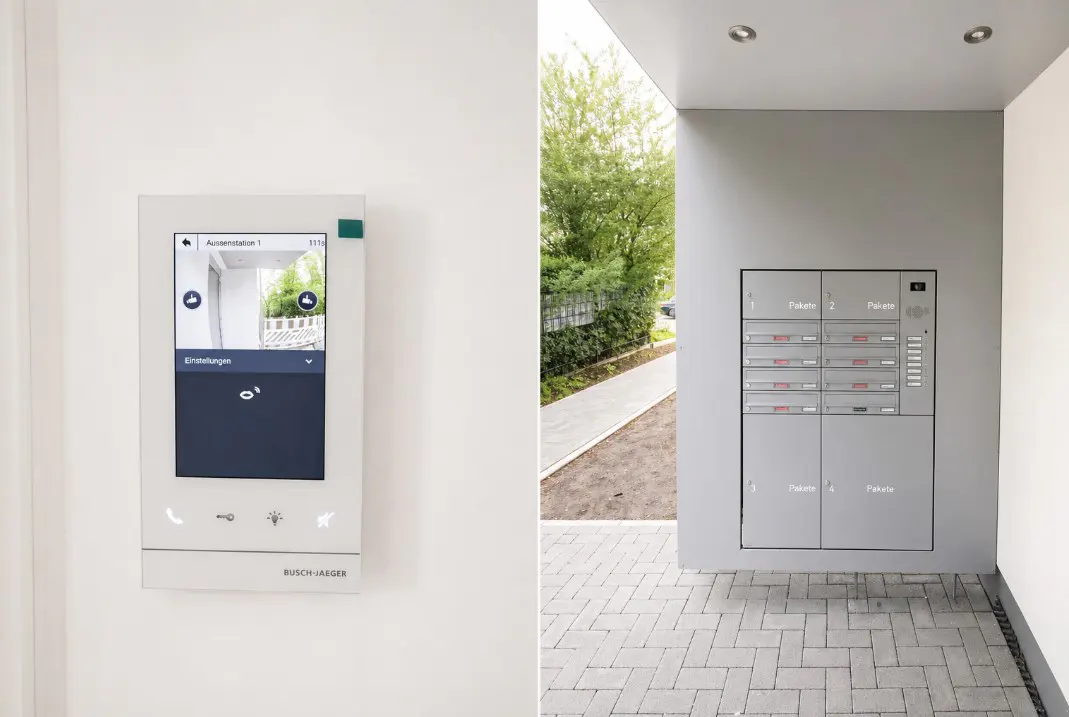 A modern apartment building entrance with a video intercom system and mailboxes.