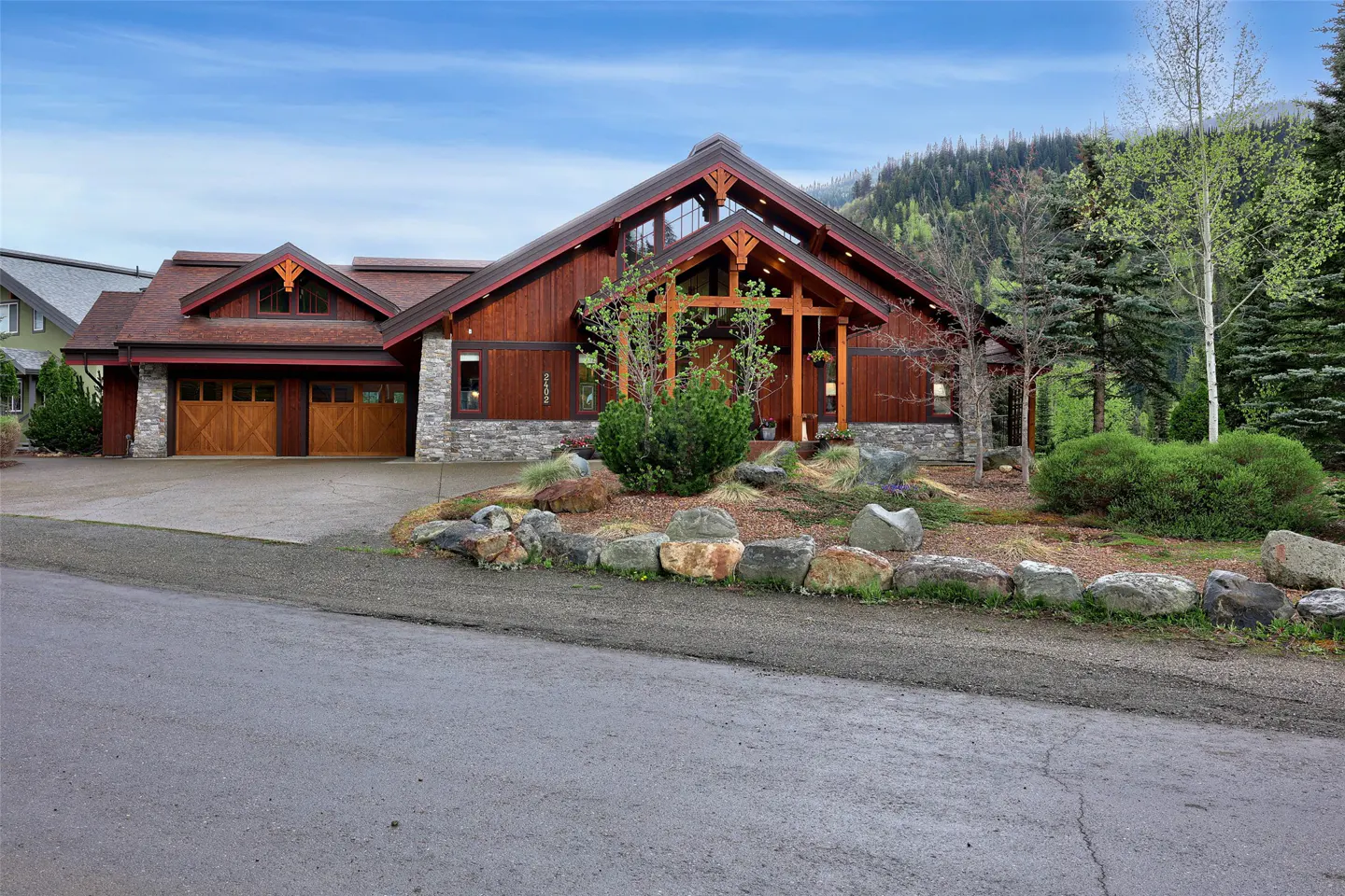 A two-story wood and stone house with a two-car garage and a landscaped yard.