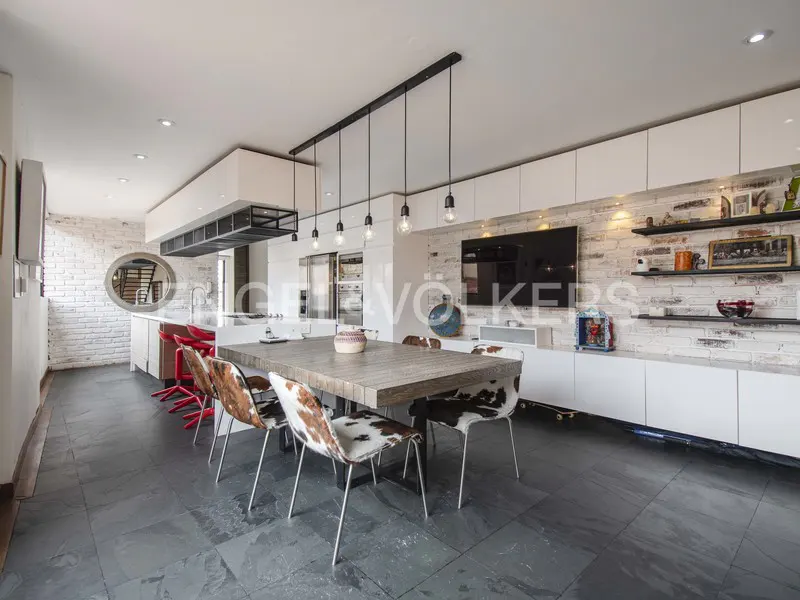 Open-concept kitchen and dining area with white brick walls, white cabinets, and cowhide chairs.