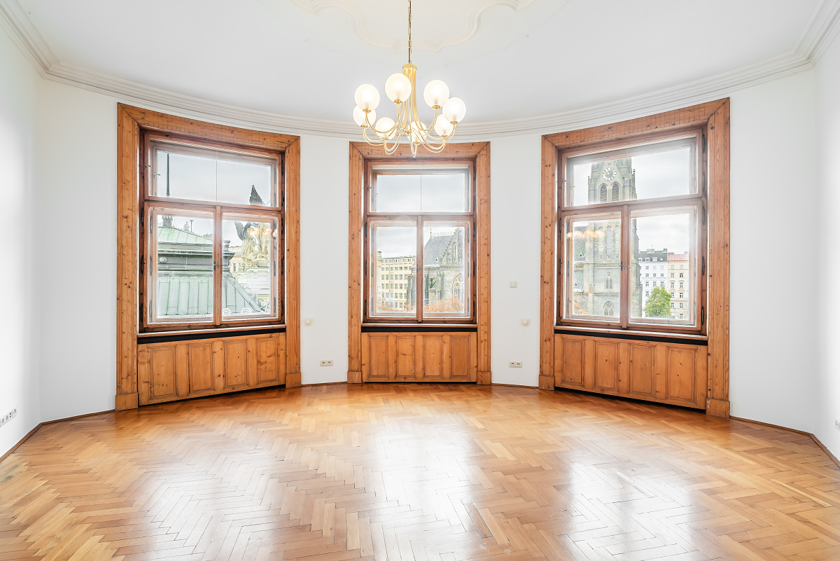 Bright room with herringbone wood floors, three large windows with wooden frames, and a modern globe chandelier.