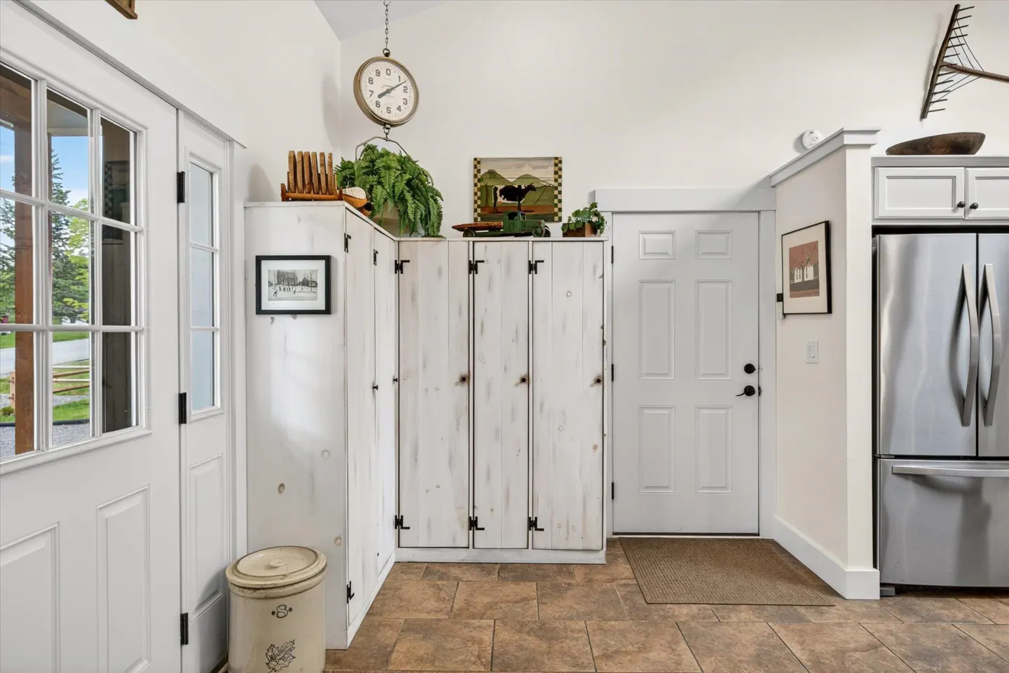 White rustic lockers in a kitchen with a stainless steel refrigerator, tiled floor, and farmhouse decor.