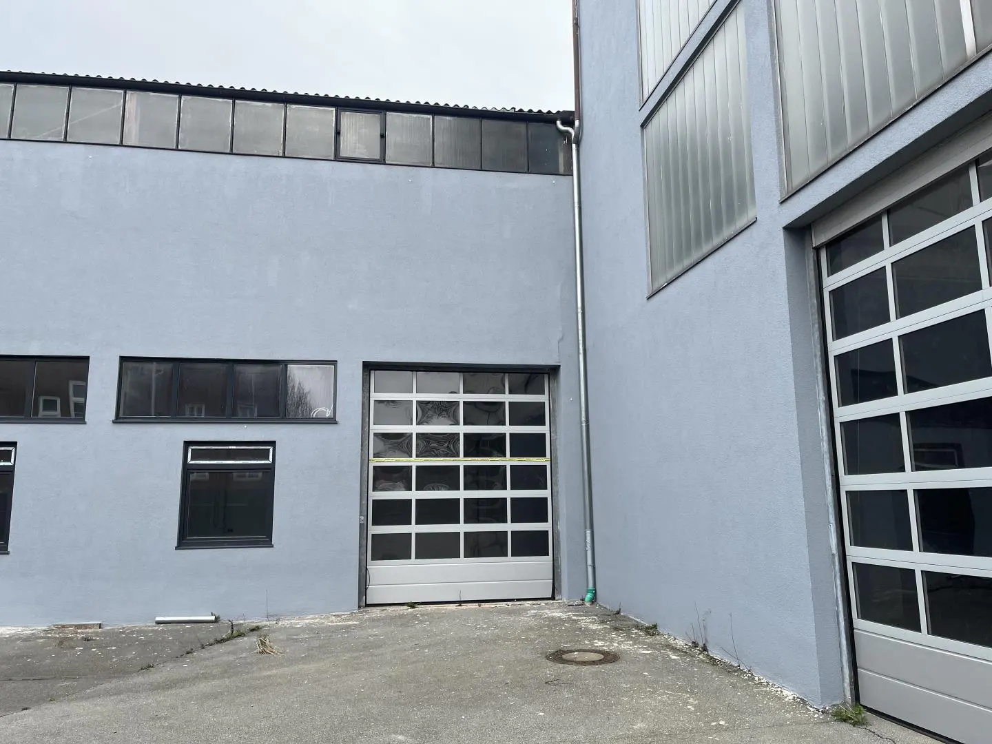 Exterior of a light blue commercial building with garage doors and windows.