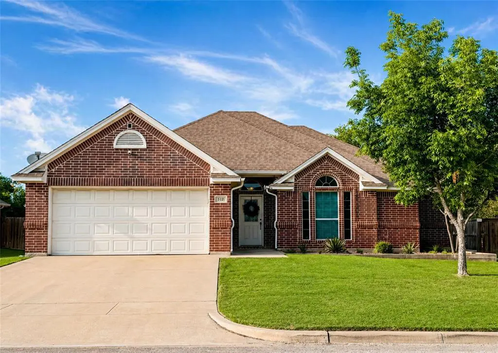 A single-story brick house with a white garage door, a brown roof, and a green lawn under a blue sky.
