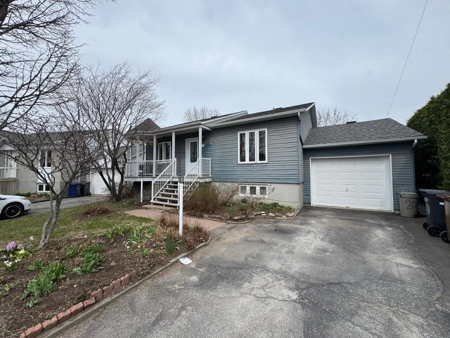 A one-story blue house with white trim, a front porch, and an attached garage.