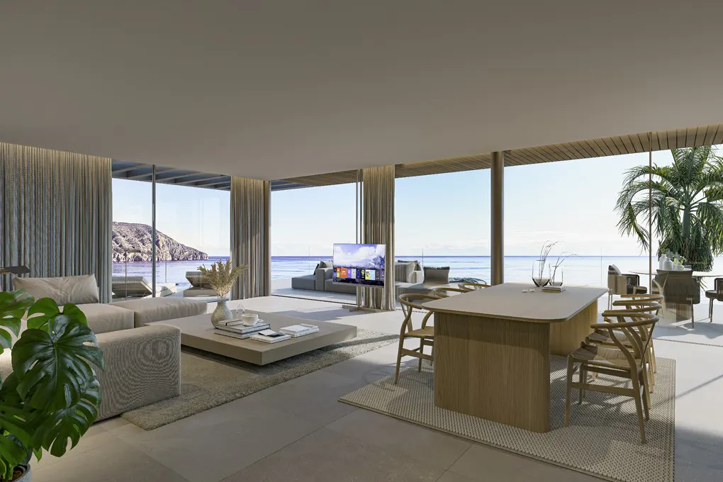 A modern, open-concept living space with a beige sectional sofa, wood dining table, and ocean views through large windows.