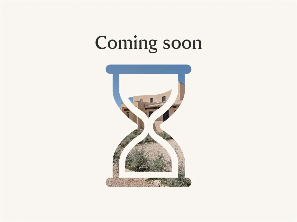 "Coming soon" text above a blue hourglass filled with a tan house and desert landscape on a cream background.