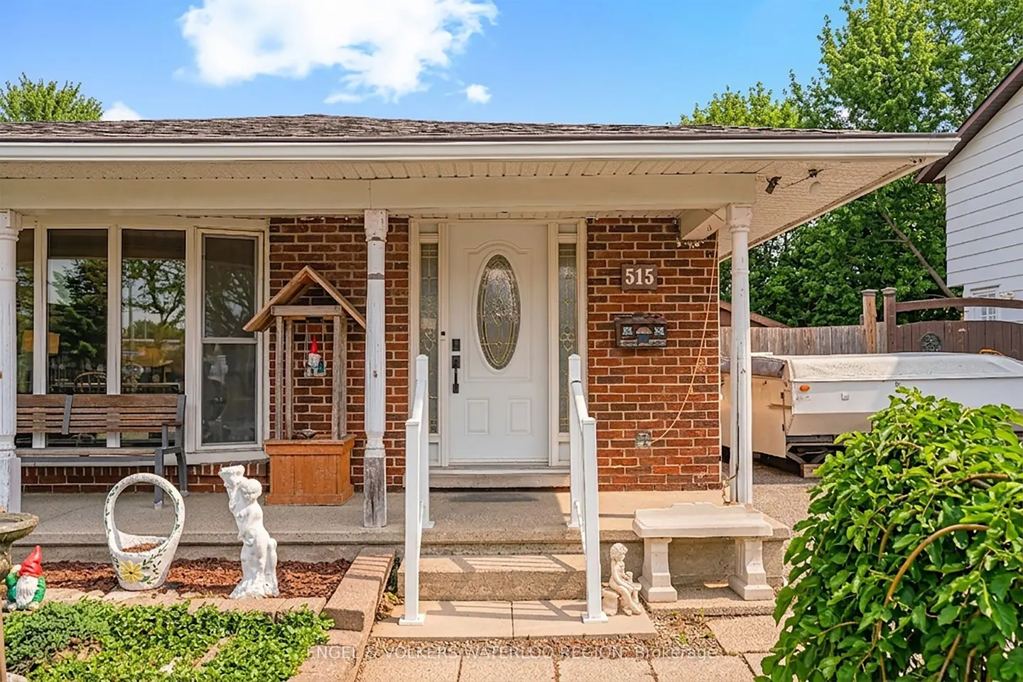 Front view of a brick house with a white door, porch, and garden. Number 515 is visible above the mailbox.
