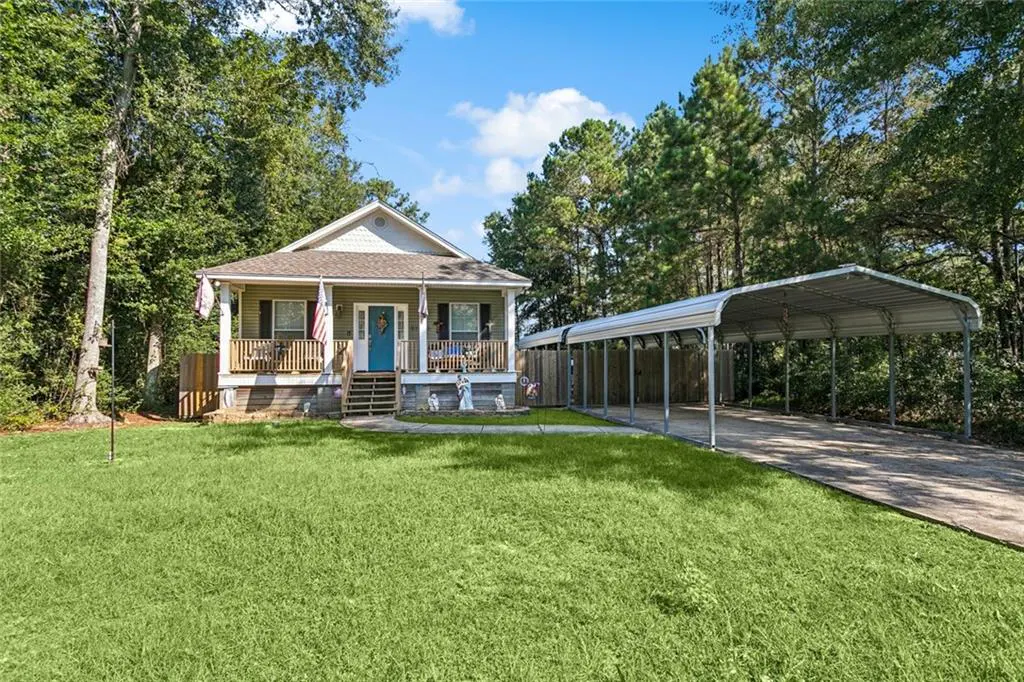 A one-story house with a blue door, a porch, and a metal carport.