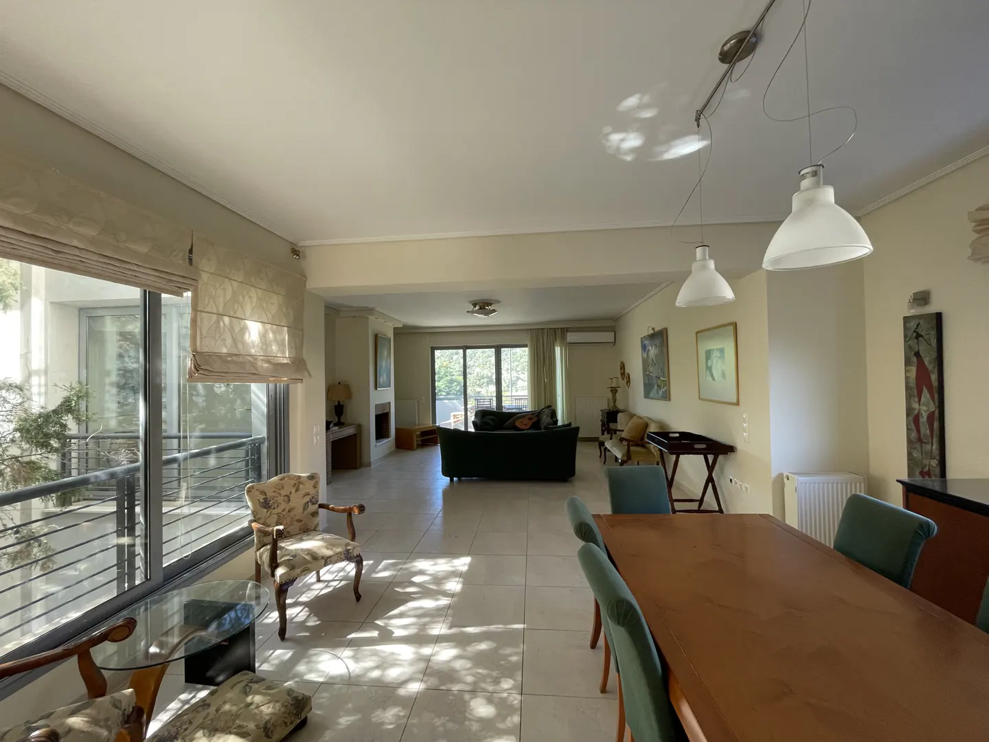 Open-concept living and dining area with a large window, wood table, and green chairs.