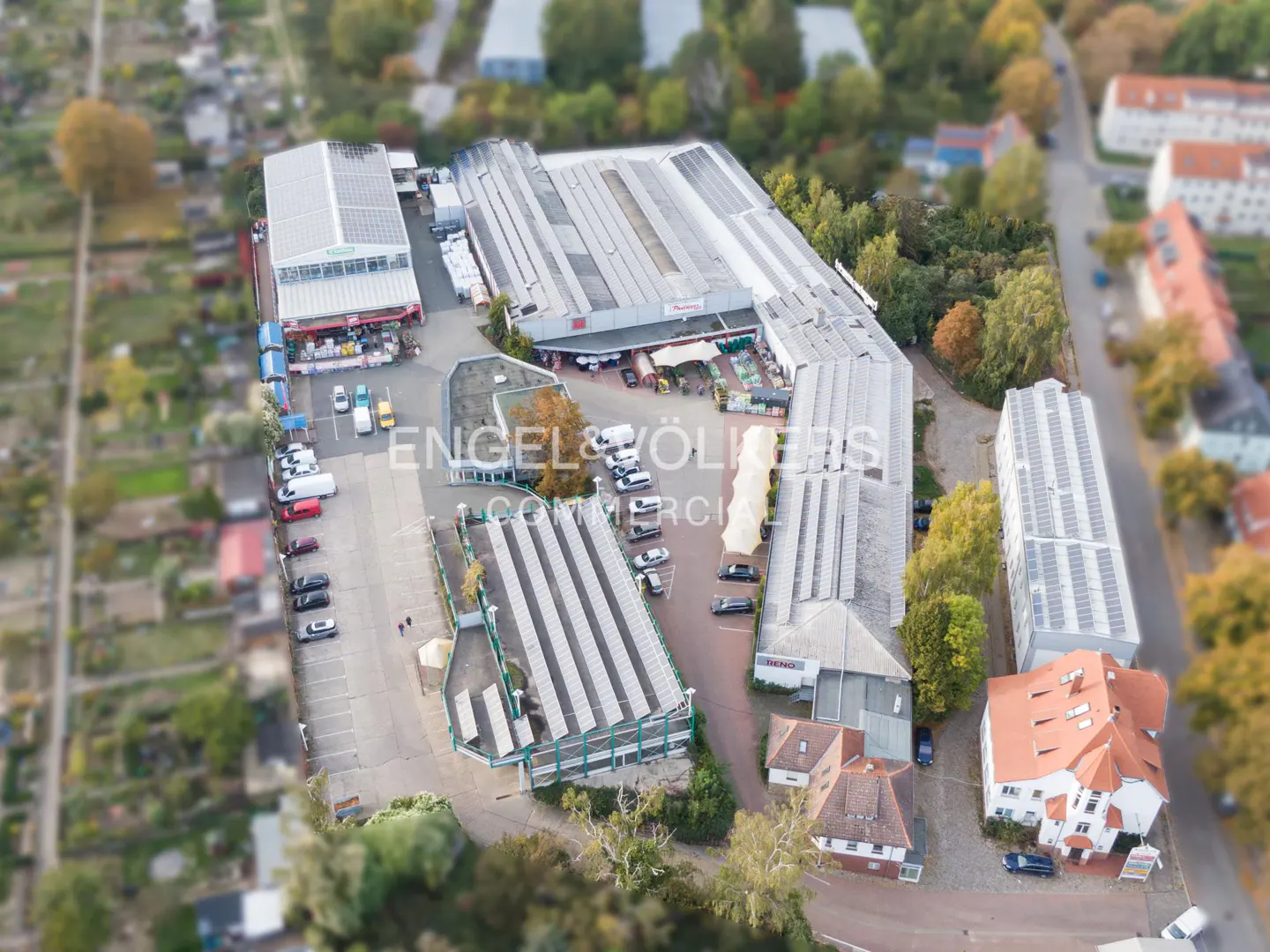 Aerial view of a commercial complex with multiple warehouse buildings, parking lots, and surrounding residential areas.