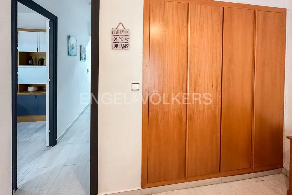Interior view of a room with a large wooden wardrobe, a doorway leading to another room, and a motivational sign on the wall.