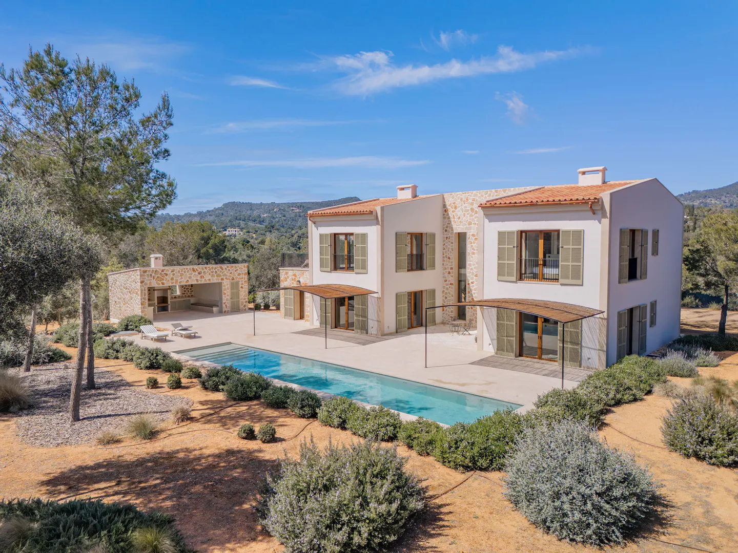 Two-story white house with a red tile roof, green shutters, and a pool in the backyard.