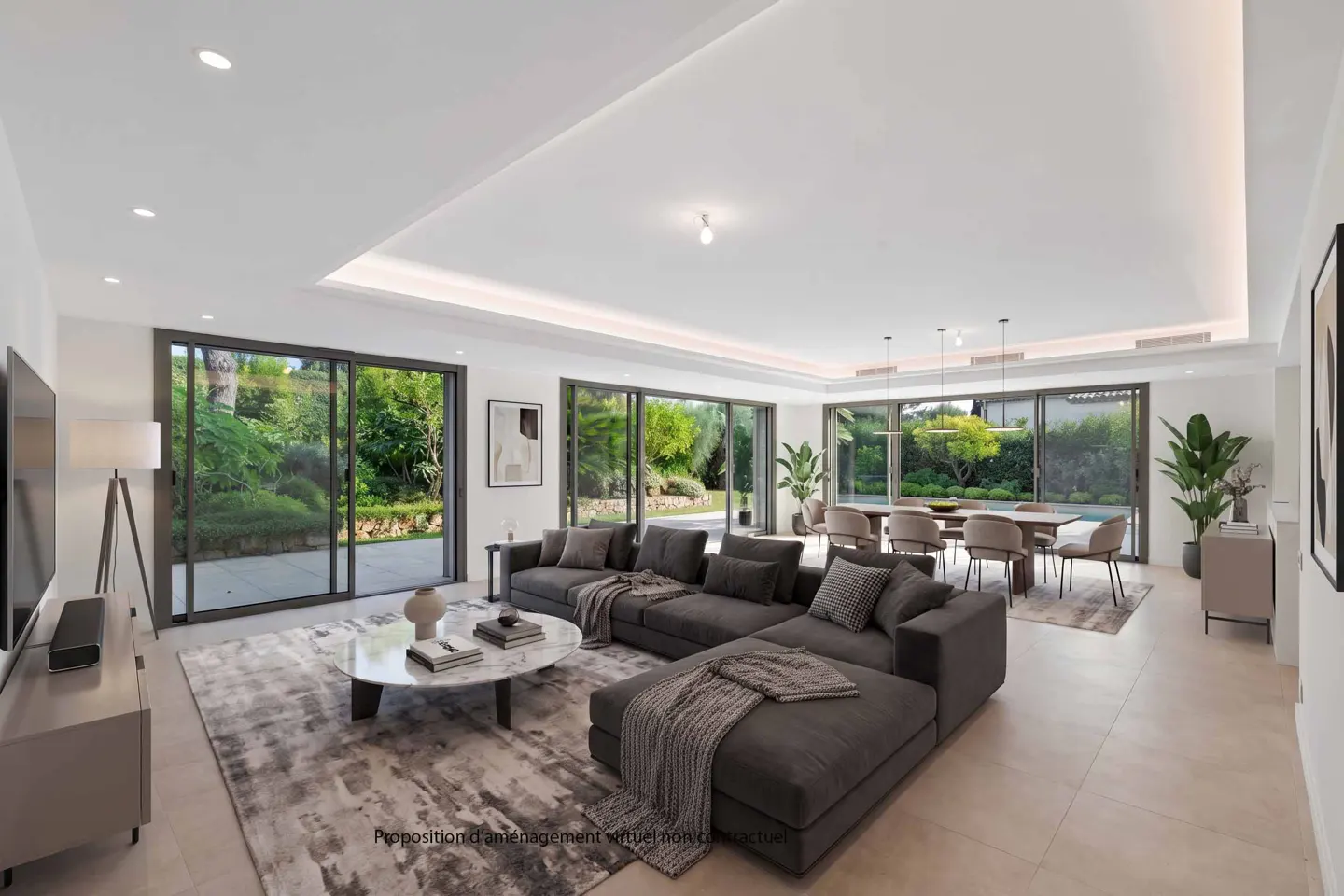 Bright, open-plan living and dining area with a large gray sectional sofa, marble coffee table, and floor-to-ceiling windows overlooking a lush garden.