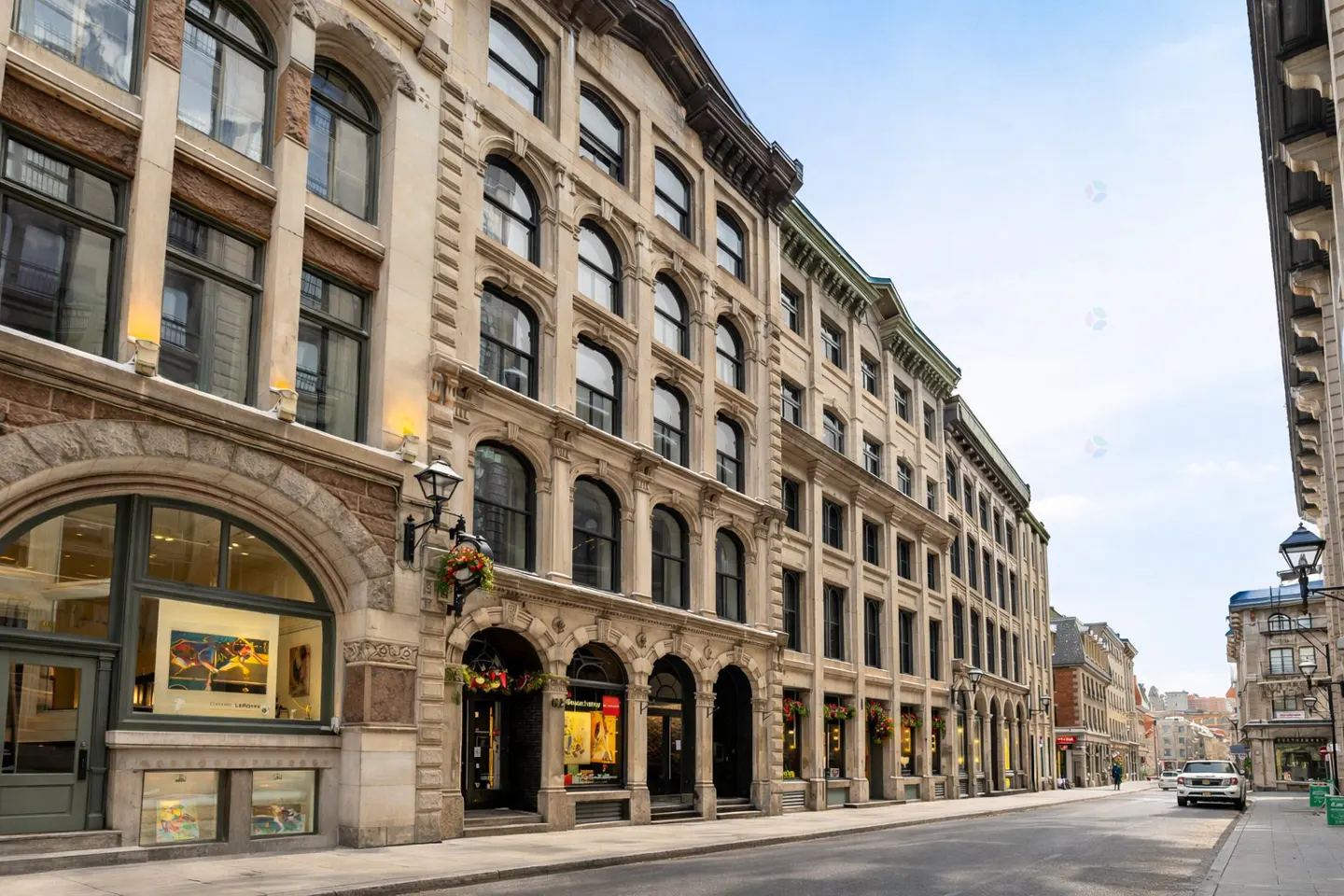 Street view of historic buildings with arched windows and storefronts on a sunny day.