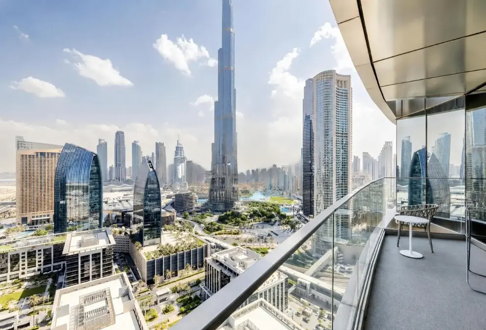 Balcony view overlooking the Dubai skyline, featuring the Burj Khalifa and modern skyscrapers under a bright blue sky.