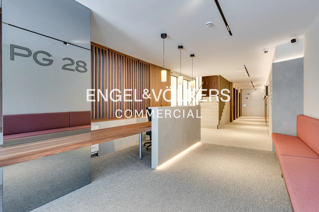 Engel & Völkers Commercial office lobby with wood accents, a reception desk, and pink seating.