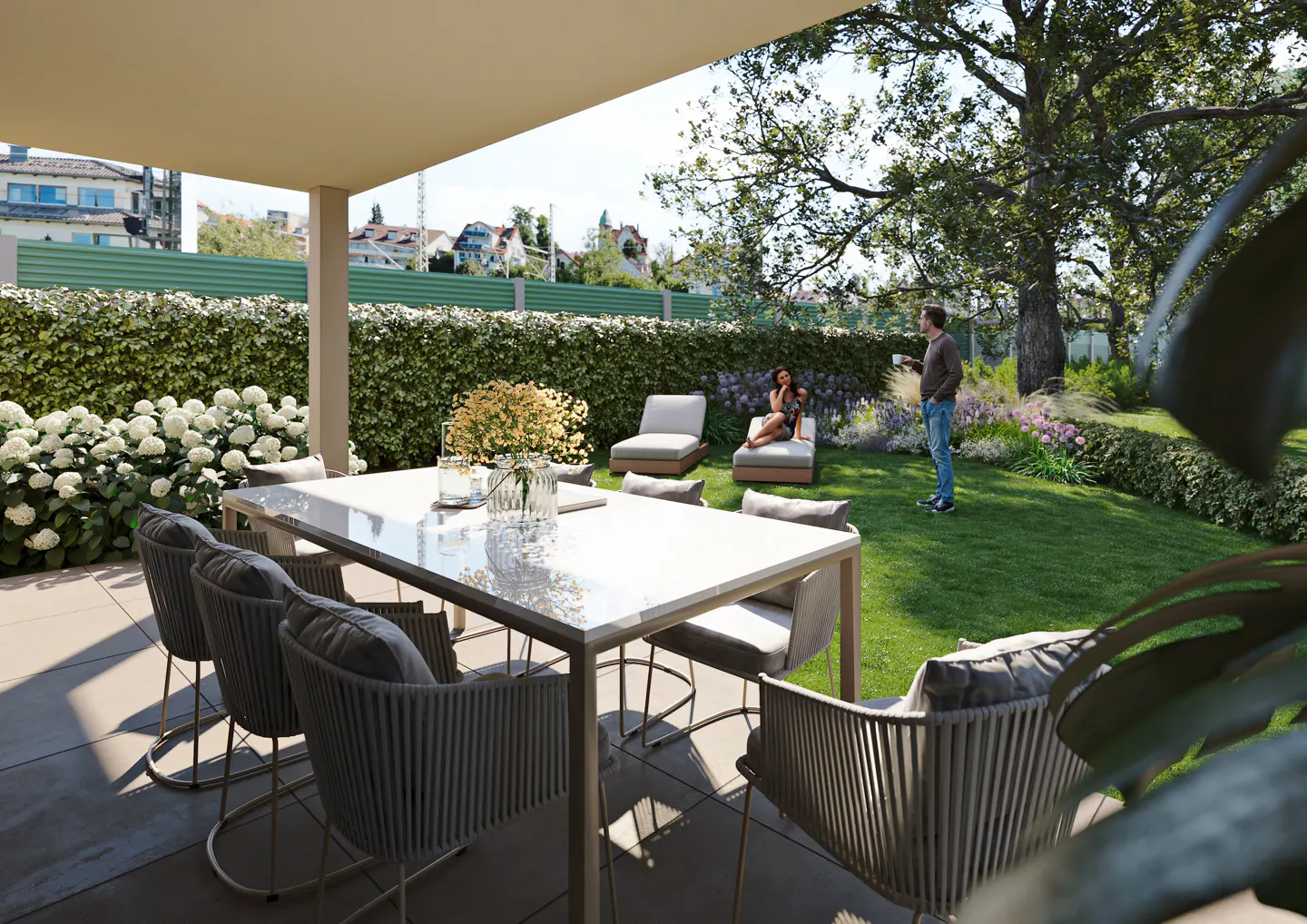 Outdoor patio with a white table, gray chairs, and a green lawn. A woman and child sit on lounge chairs in the background.
