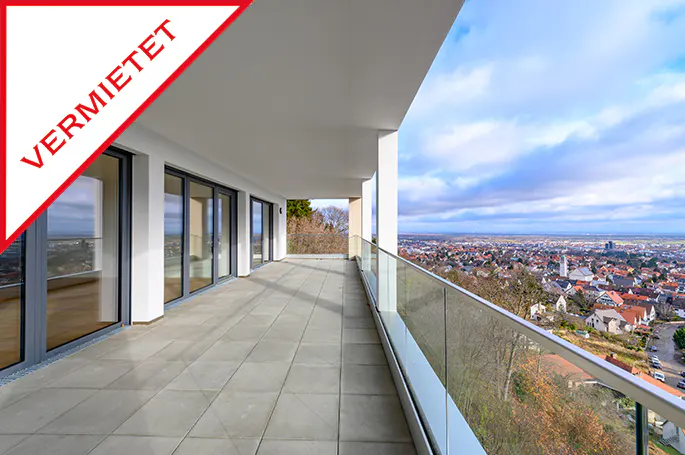 A long balcony with glass railings overlooks a city. A red "VERMIETET" banner is in the corner.