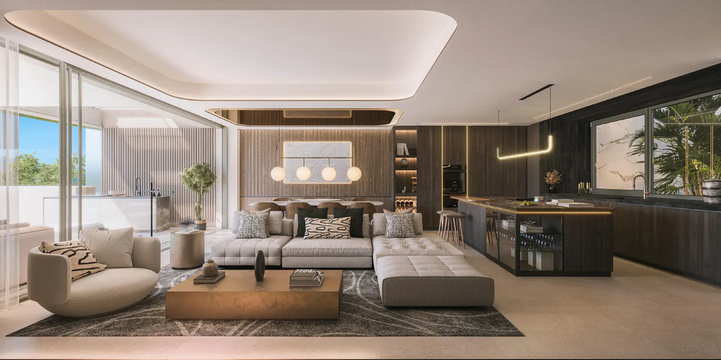 A modern living room with a gray sectional sofa, a gold coffee table, and a kitchen island with dark wood cabinets.