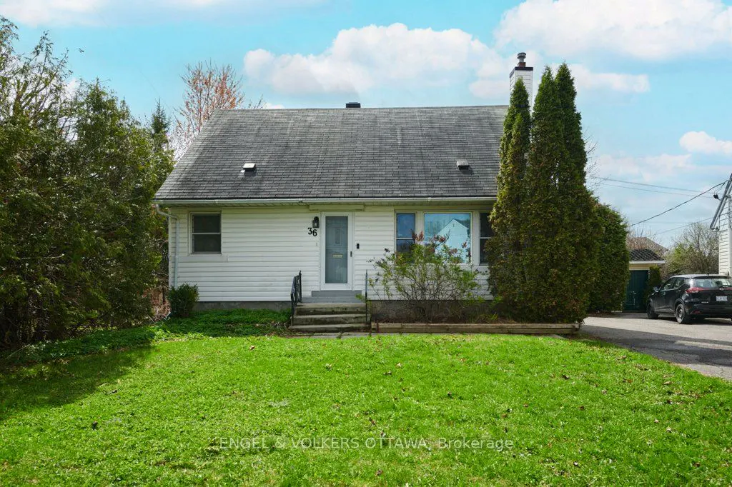 A white, one-story house with a gray roof, green lawn, and trees under a blue sky.