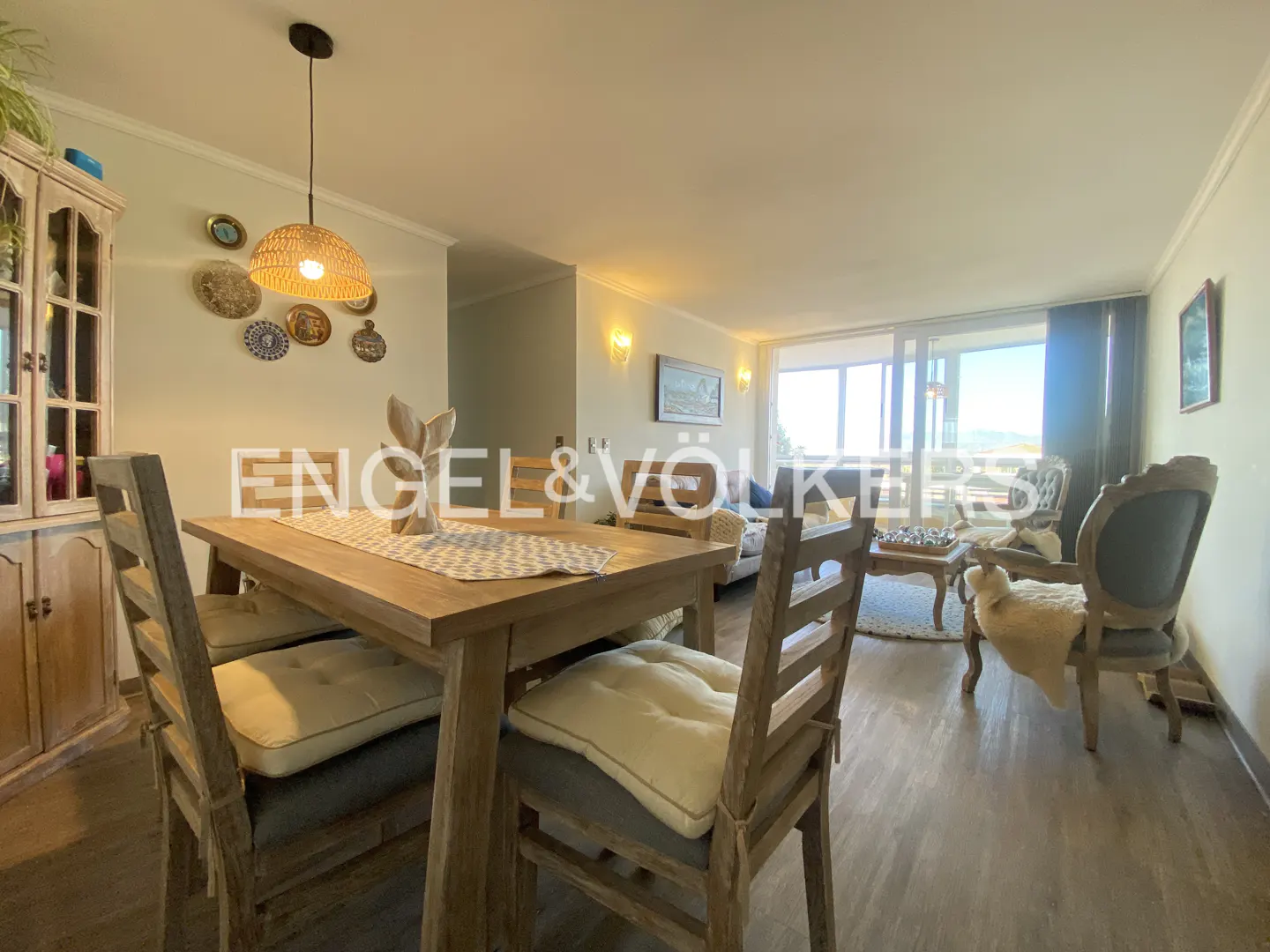A bright, open-concept living and dining area with wood floors, a dining table with chairs, and a living room with a view.