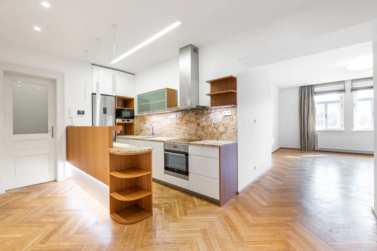 Bright, modern kitchen with white cabinets, stainless steel appliances, and wood floors. A breakfast bar with open shelving divides the space.