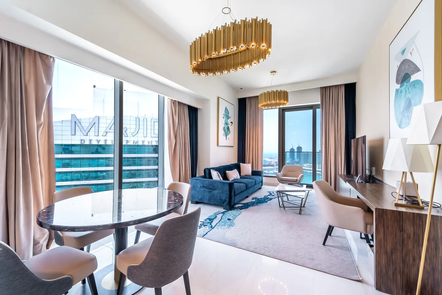 Modern living room with a blue sofa, marble dining table, and floor-to-ceiling windows overlooking a city skyline.