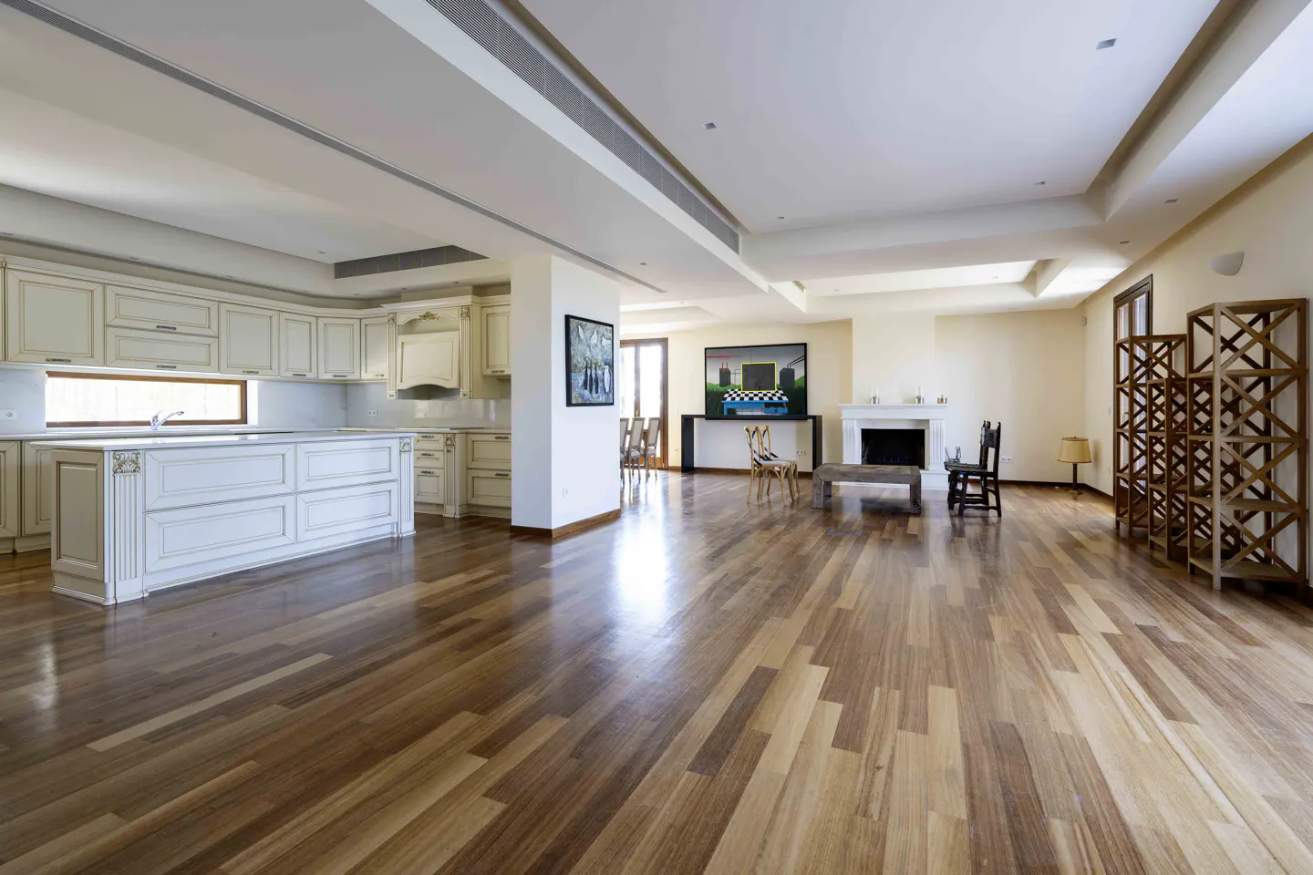 Open-concept living space with hardwood floors, cream cabinets, fireplace, and modern art.