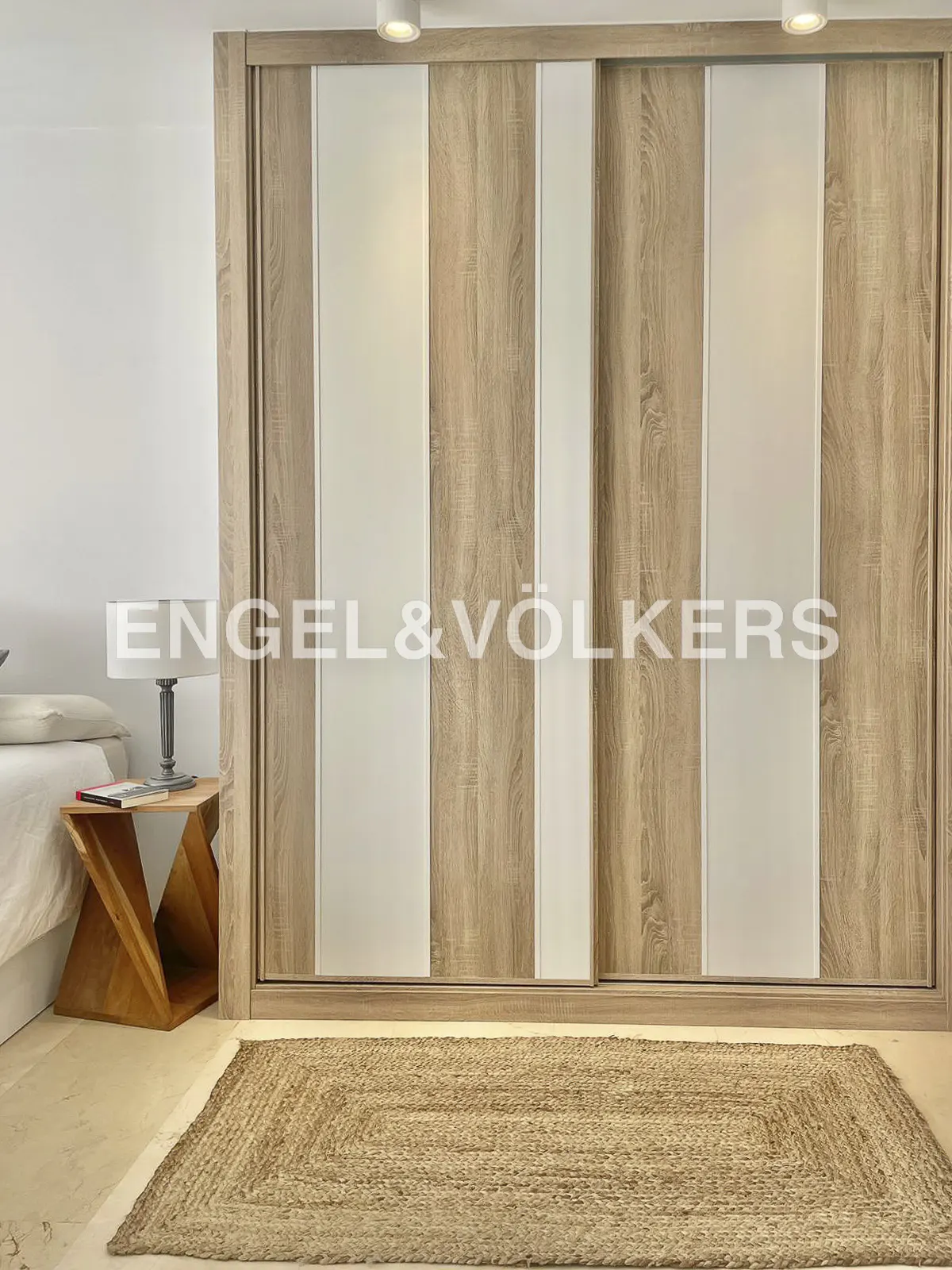 Bedroom with a large closet with sliding doors, a wooden side table, and a jute rug.
