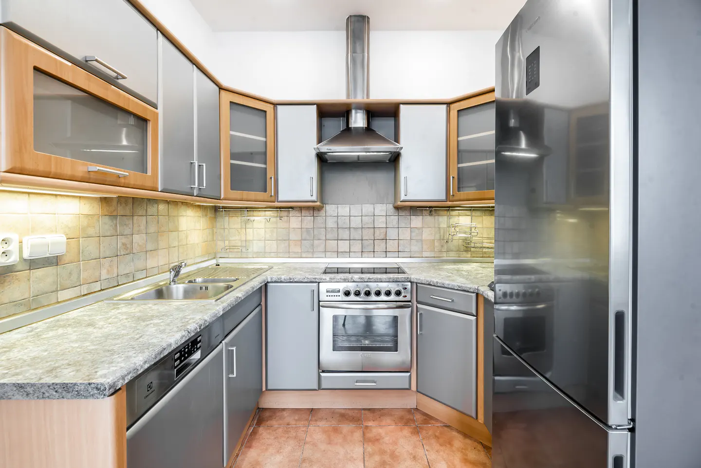 A well-lit kitchen with gray cabinets, stainless steel appliances, and tile backsplash.