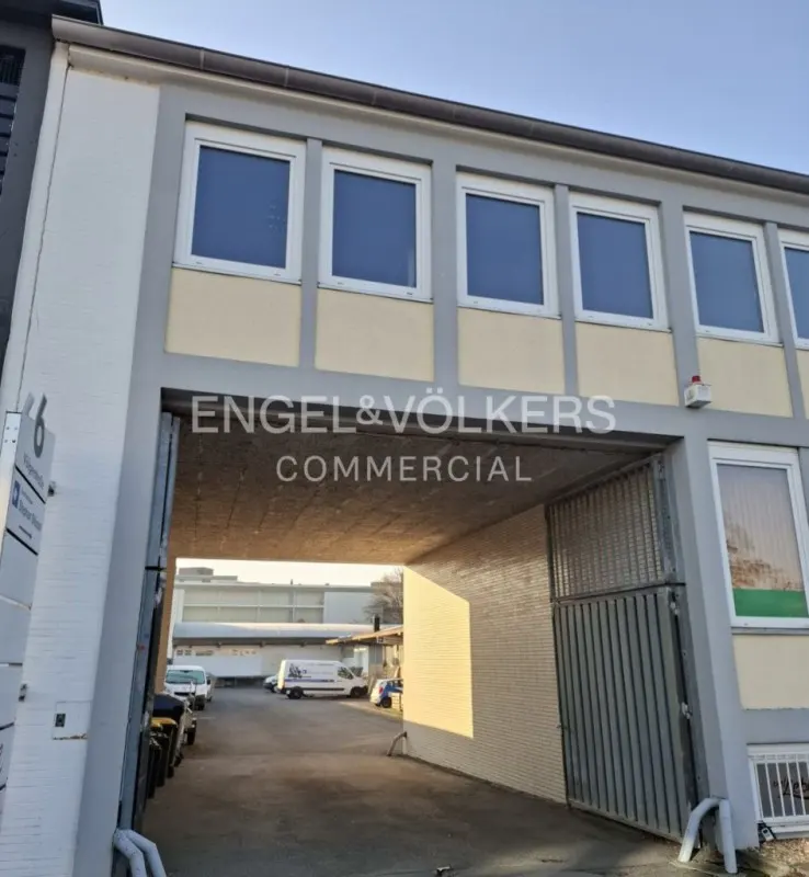 Exterior view of an Engel & Völkers Commercial building with a gray entrance tunnel and a metal gate. Windows are visible above the tunnel.