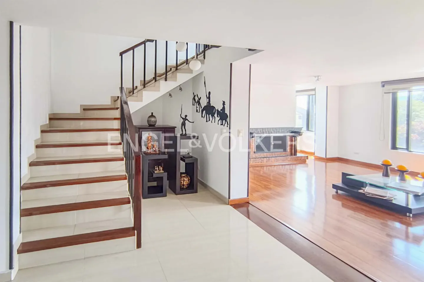 Interior view of a home with a staircase, dark wood furniture, and hardwood floors. The walls are white.